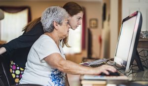 Active Silver Haired Senior Woman Browsing Social Media Together With Her Granddaughter  Teenager Girl